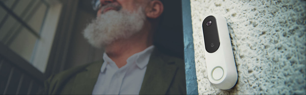 Man with a beard looking at a the Doro Hemma doorbelldevice on a wall.